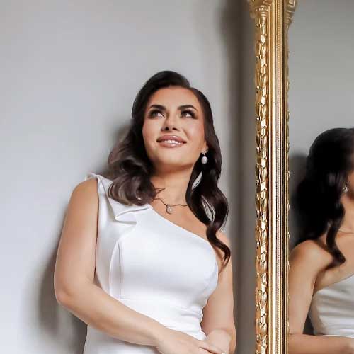 scm-review-alesya A woman in a white dress looking at a mirror.