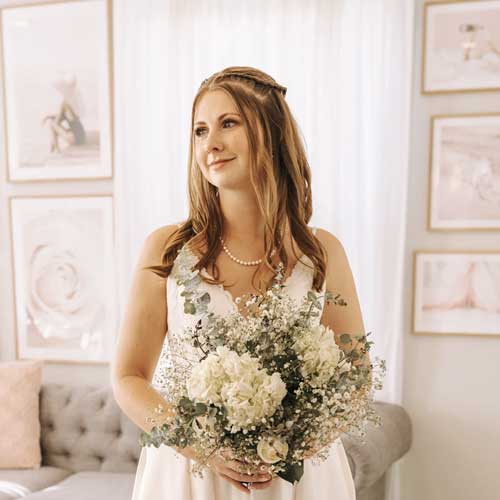 scm-review-meghan A woman in a white dress holding a bouquet of flowers.