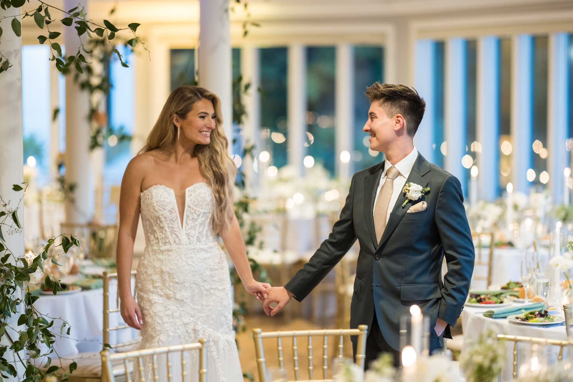 brides-smiling-at-wedding-reception-at-sea-cliff-manor A man and woman holding hands.
