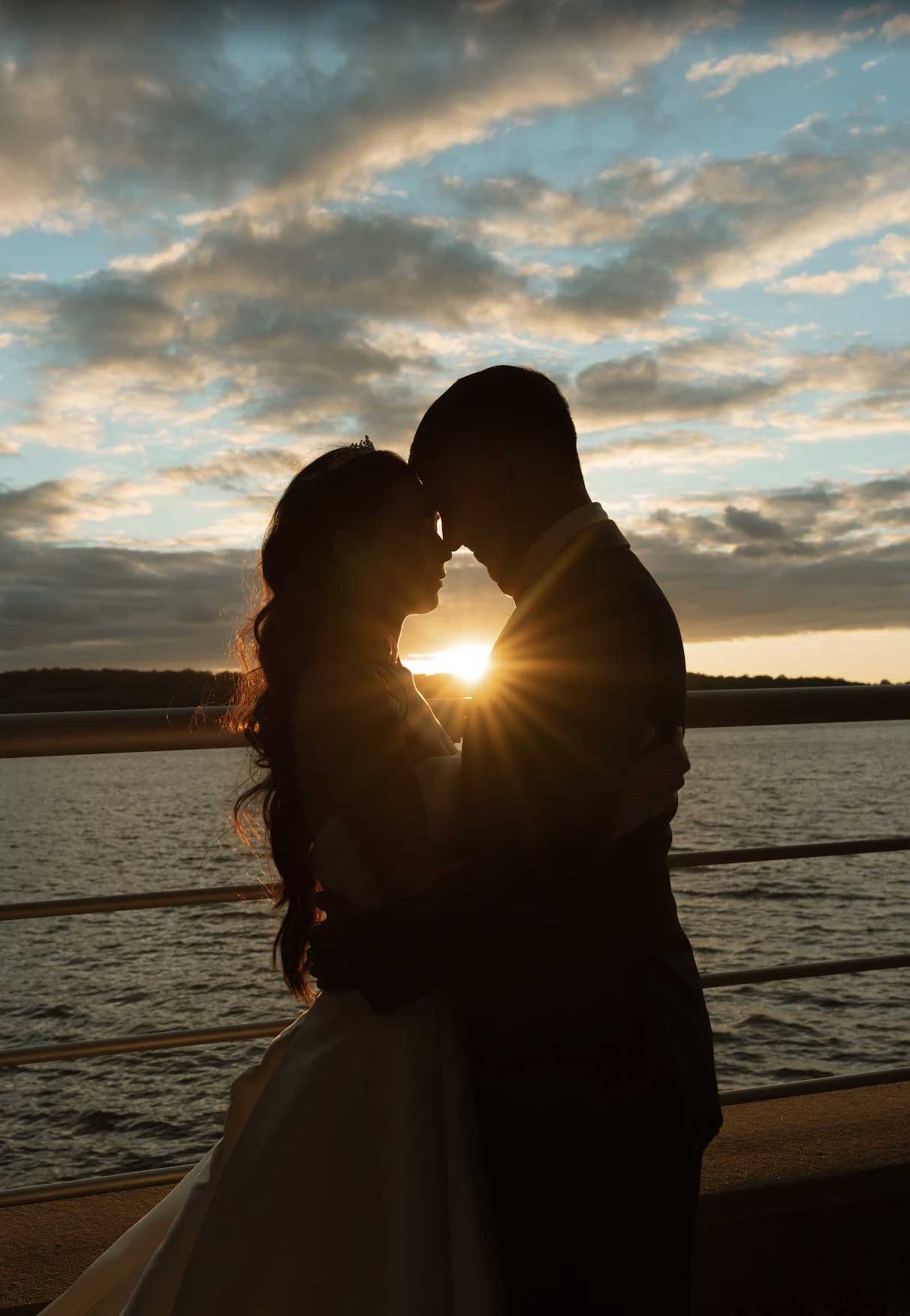 sunset-couple-along-sea-walk-sea-cliff-manor A man and woman hugging each other.